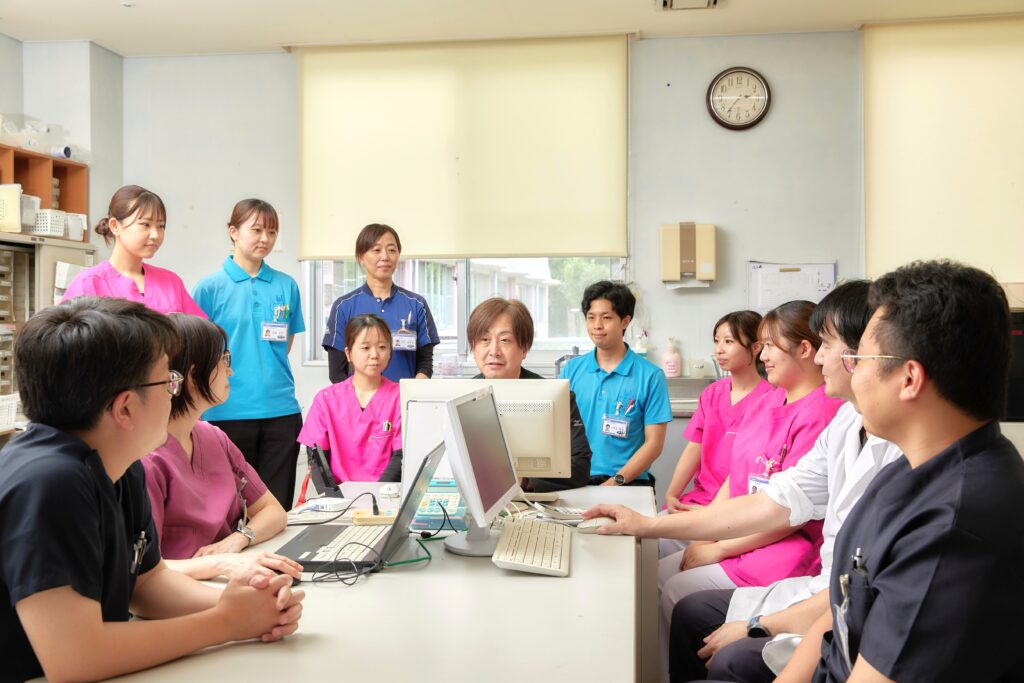 医療スタッフがパソコンを囲み業務の打ち合わせをしている様子