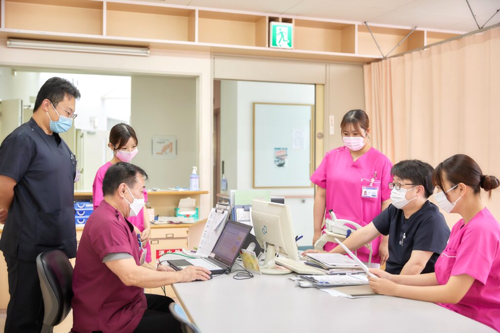 医療スタッフがパソコンを囲み業務の打ち合わせをしている様子